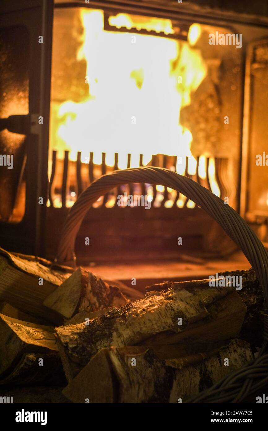 Old Basket With Wooden Logs And Fireplace With Warm Fire At The