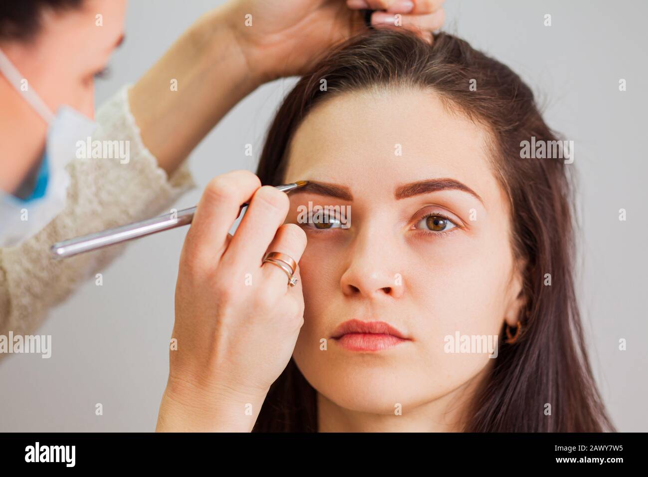 Master makeup corrects and gives shape to eyebrows in a beauty salon Stock Photo