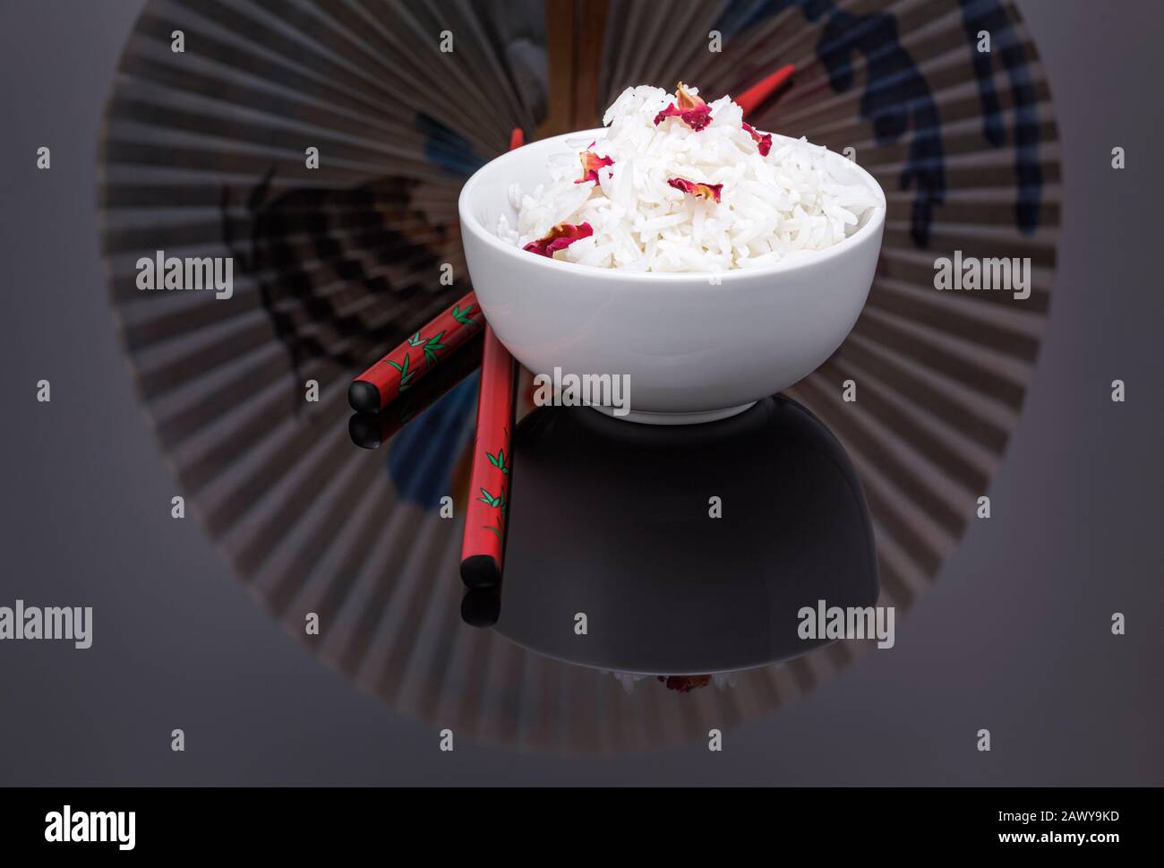 Bowl of cooked white rice garnished with edible rose petals Stock Photo