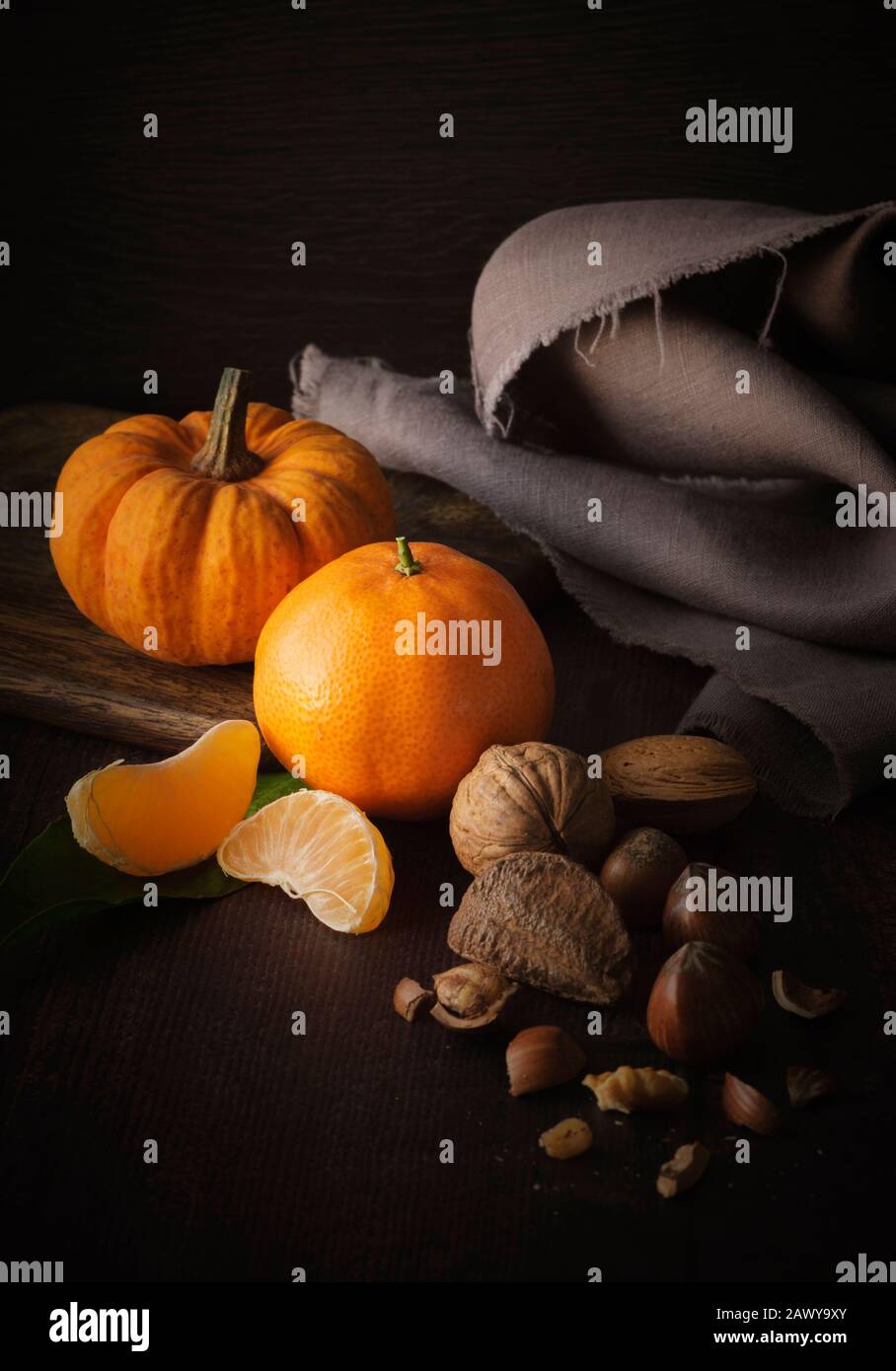 Autumn still life with mixed nuts , mini pumpkin and orange Stock Photo