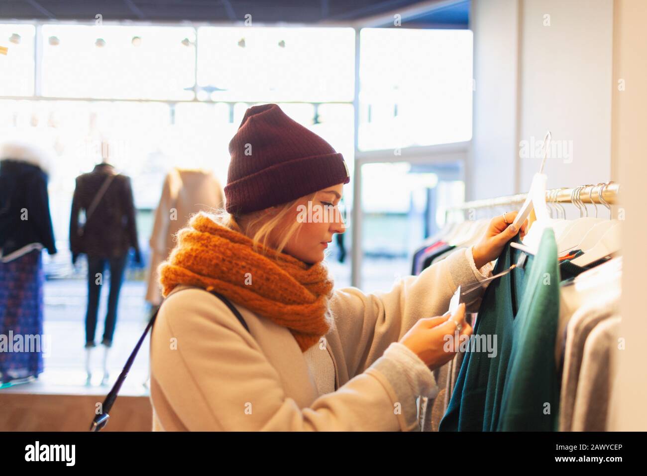 Young woman shopping in clothing store, checking price tag Stock Photo