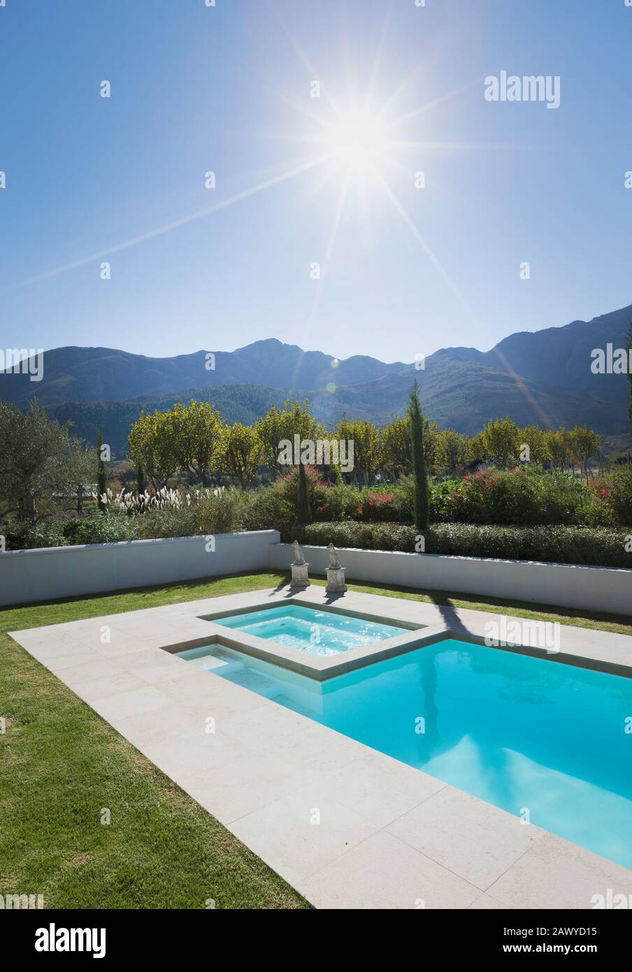 Sun shining over idyllic, tranquil lap pool with mountain view Stock Photo