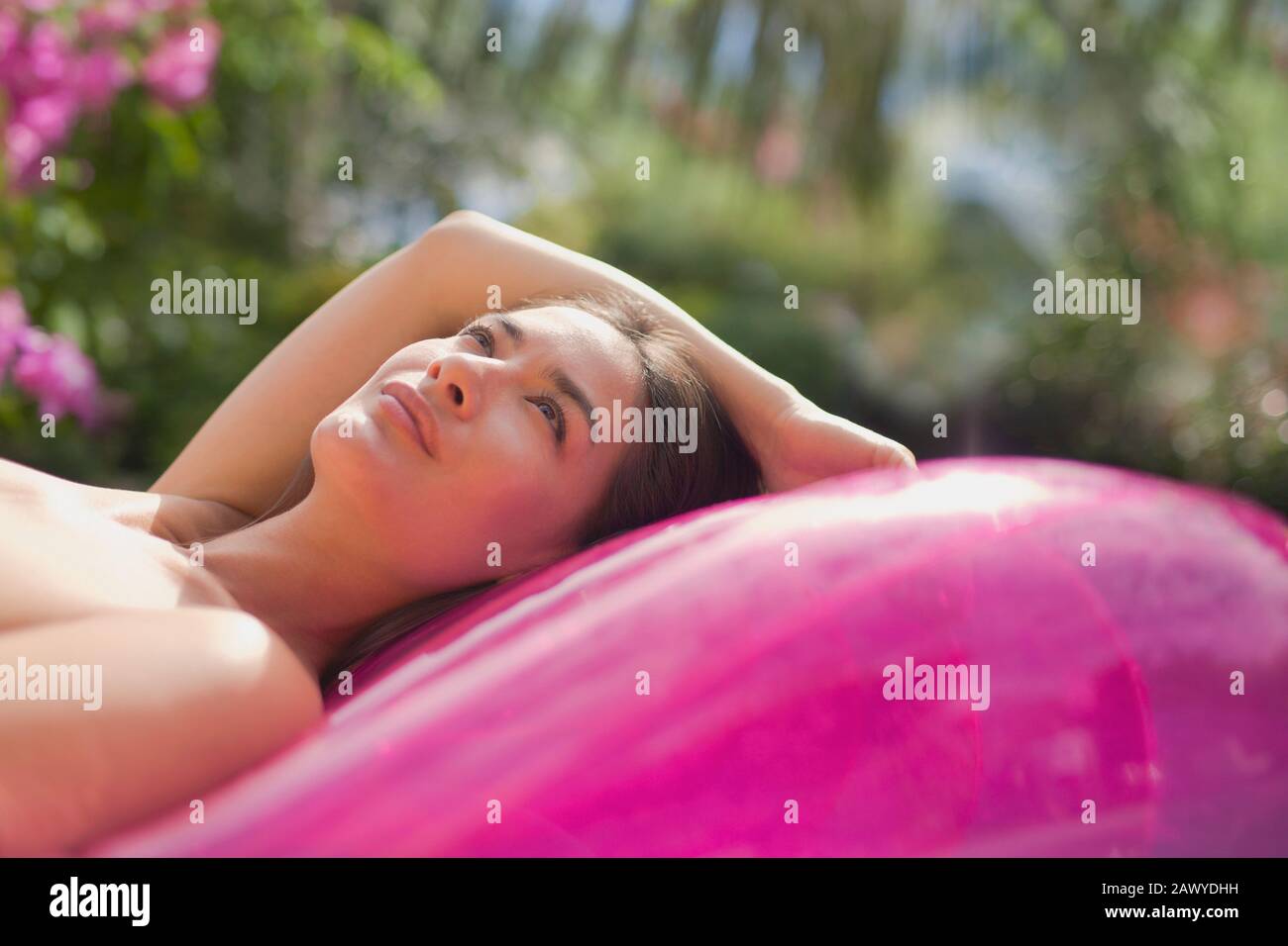 Serene woman relaxing on pink inflatable pool raft Stock Photo