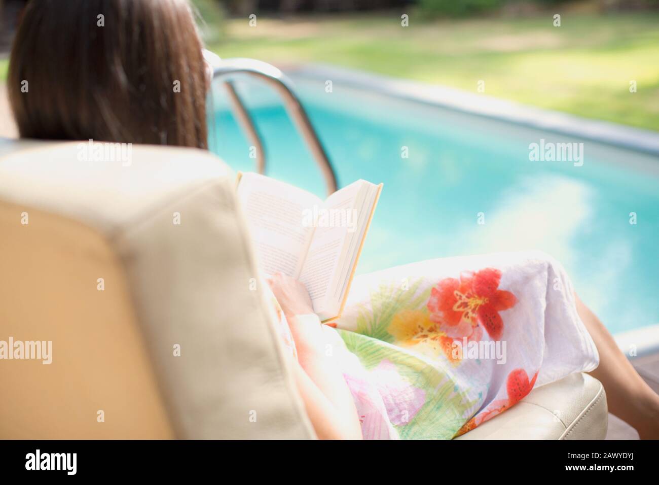 Woman relaxing, reading book at summer poolside Stock Photo