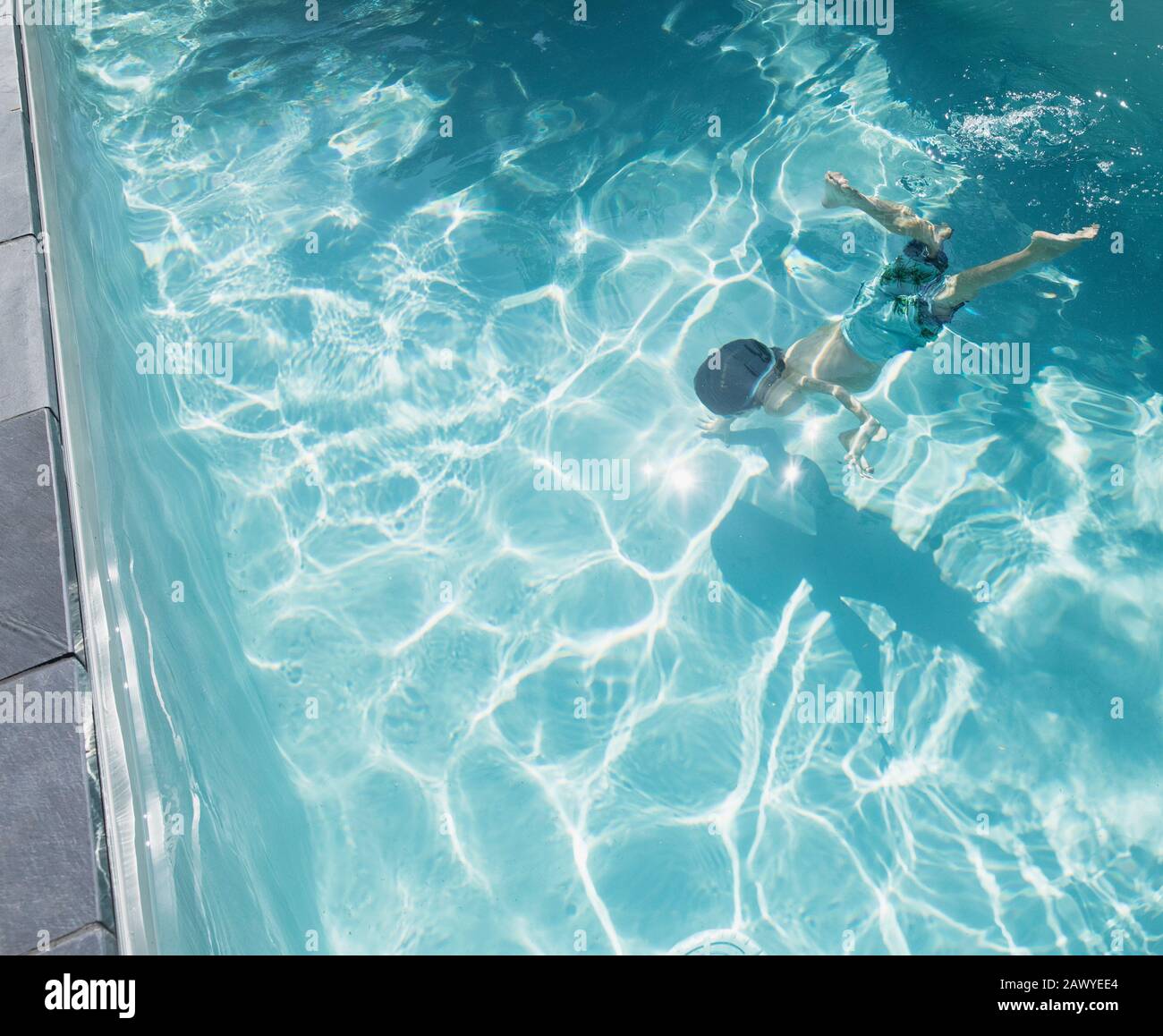 Boy swimming underwater in sunny, summer swimming pool Stock Photo