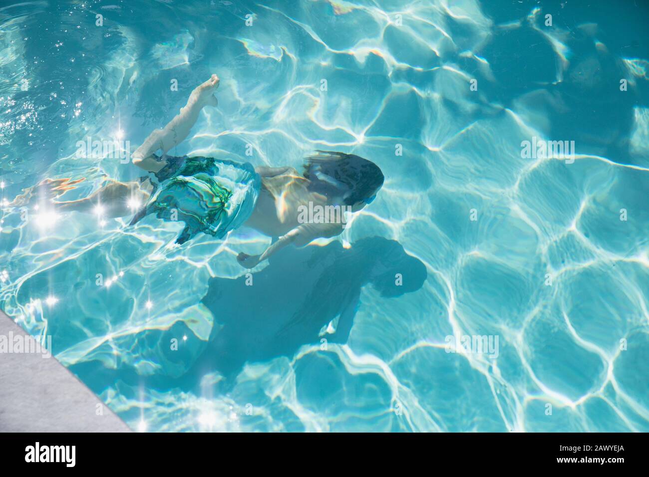 Boy swimming underwater in sunny summer swimming pool Stock Photo