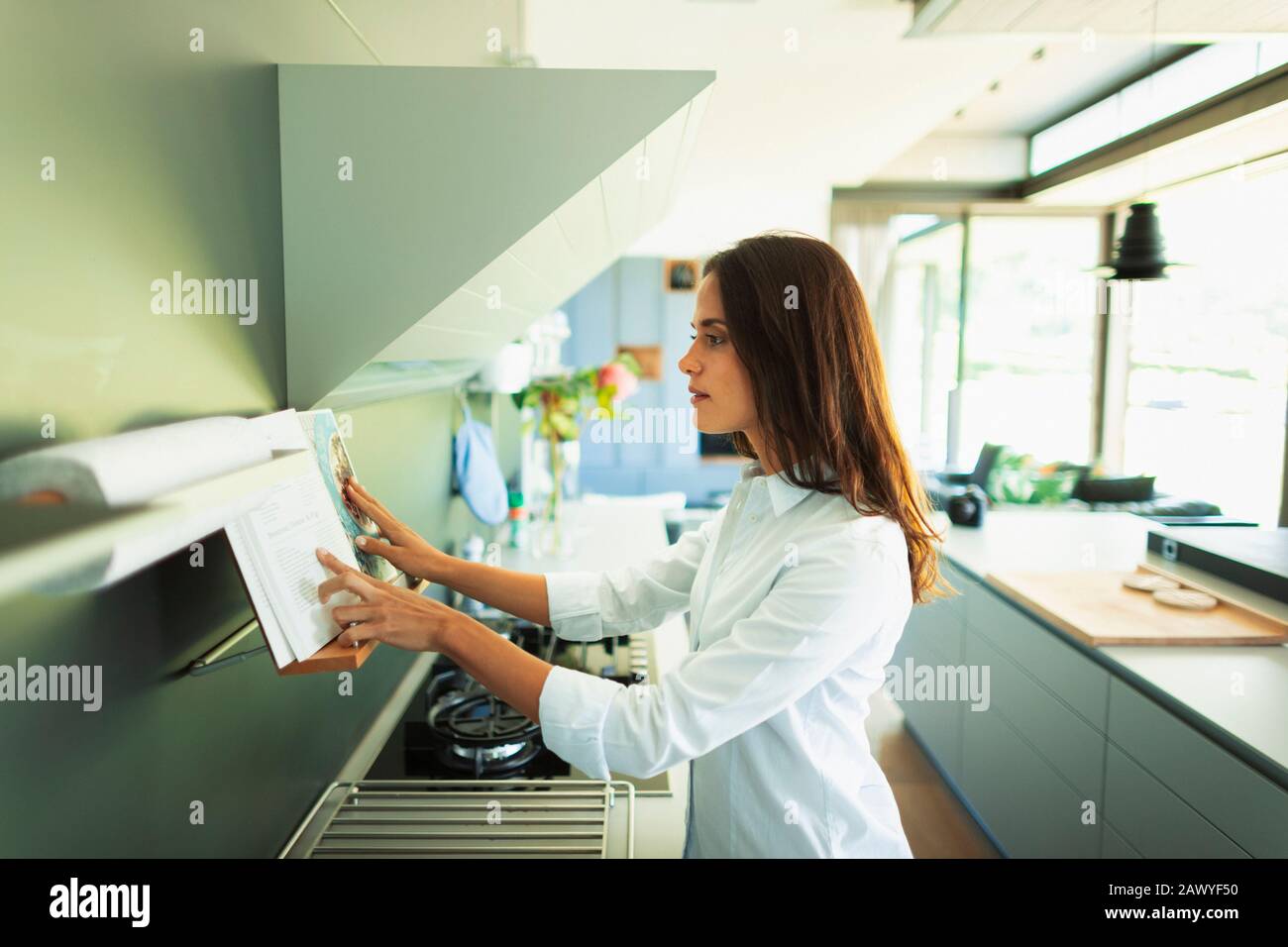 Woman checking recipe in cookbook, cooking in modern kitchen Stock Photo