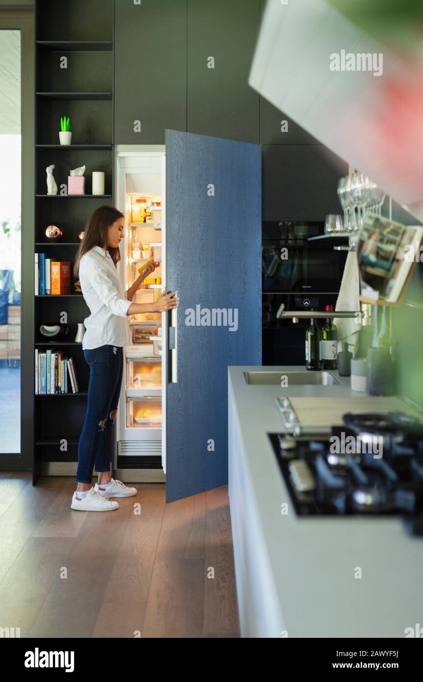 Woman standing at open refrigerator in kitchen Stock Photo