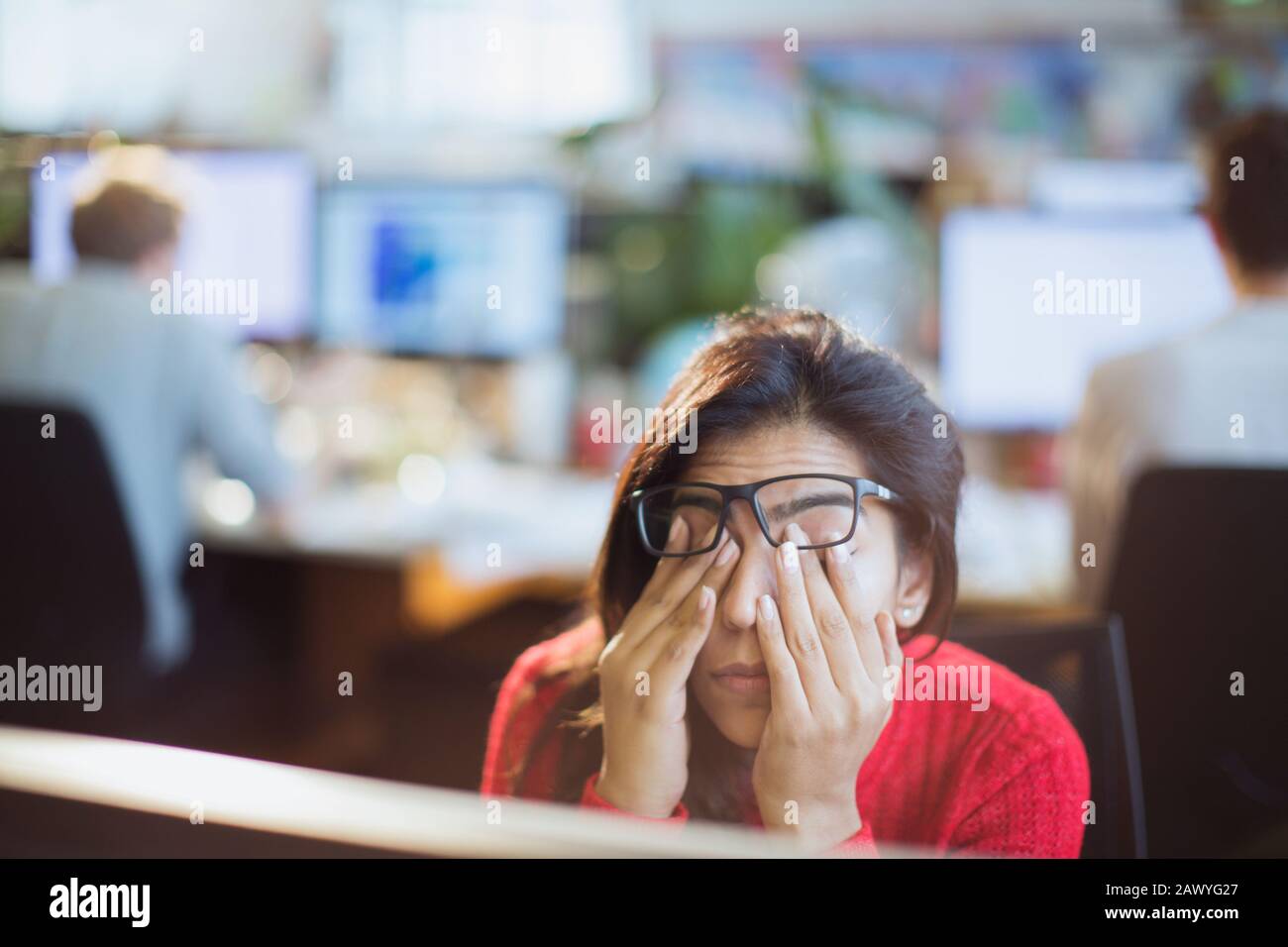 Tired, stressed businesswoman rubbing eyes in office Stock Photo