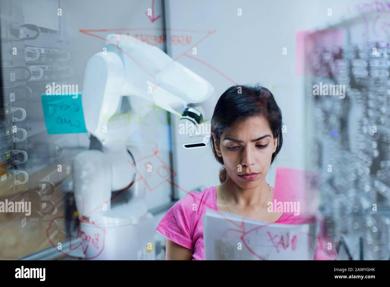 Female engineer with paperwork planning, programming robotic arm Stock Photo