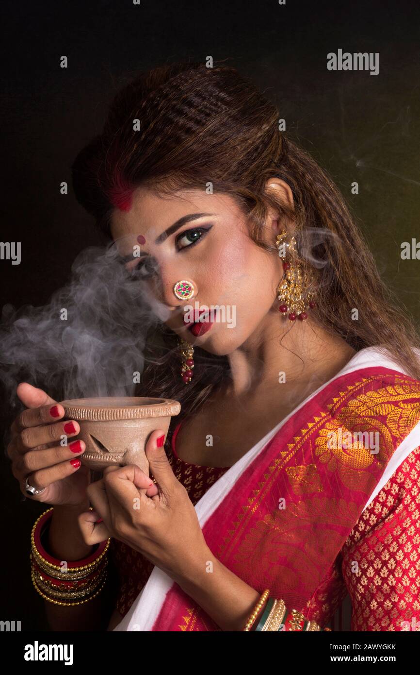 Portrait of an young and beautiful Indian Bengali woman in red and white traditional