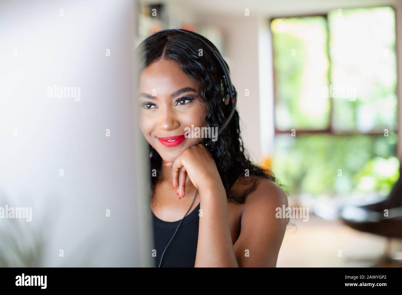 Young woman with headset working from home at computer Stock Photo