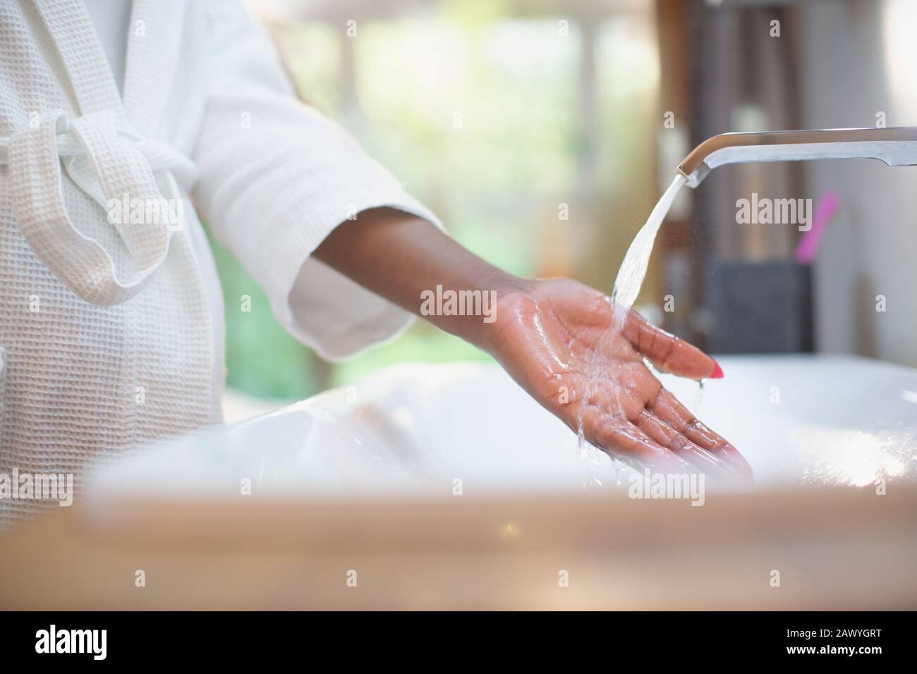 Woman with hand under bathroom water faucet Stock Photo
