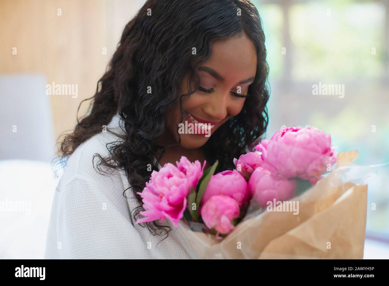 Happy young woman receiving pink peony bouquet Stock Photo