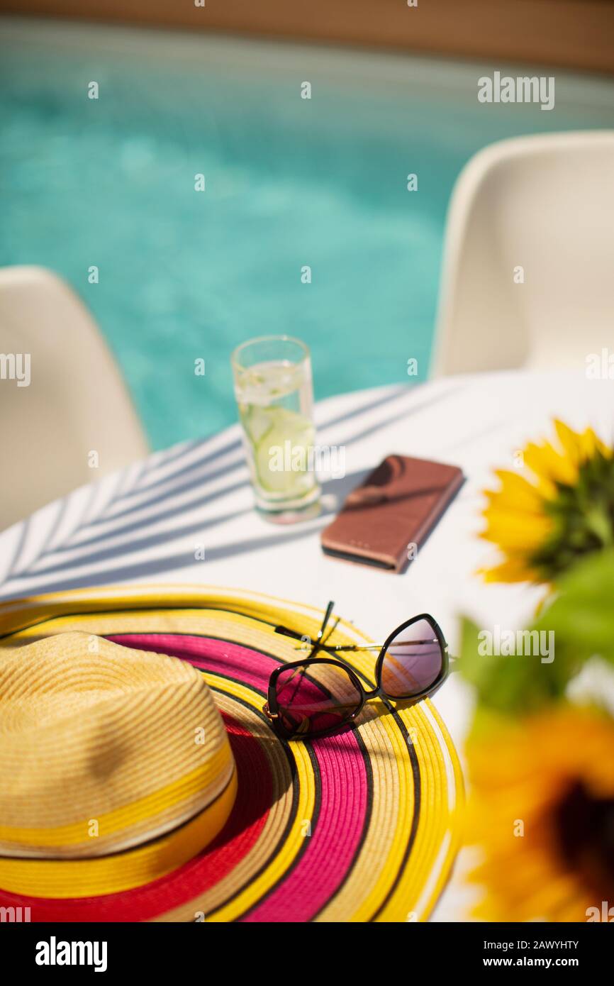 Sun hat and sunglasses on summer poolside patio table Stock Photo - Alamy