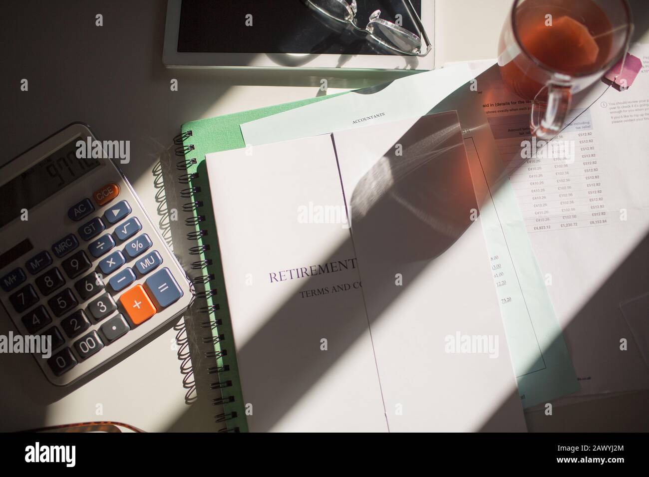 Retirement portfolio on sunny table with tea and calculator Stock Photo