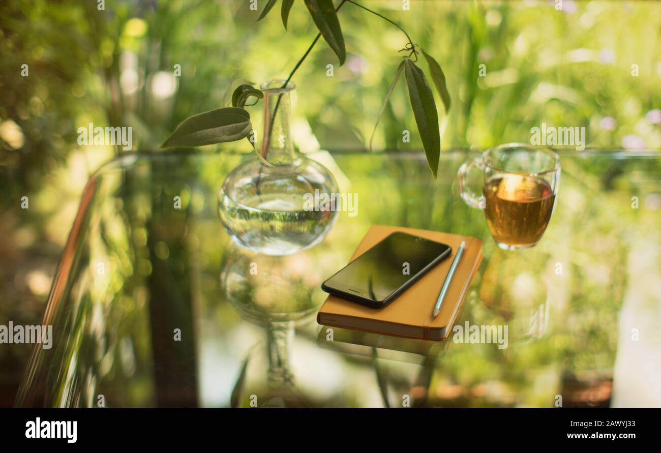 Tea and smart phone on table with notebook and vase Stock Photo