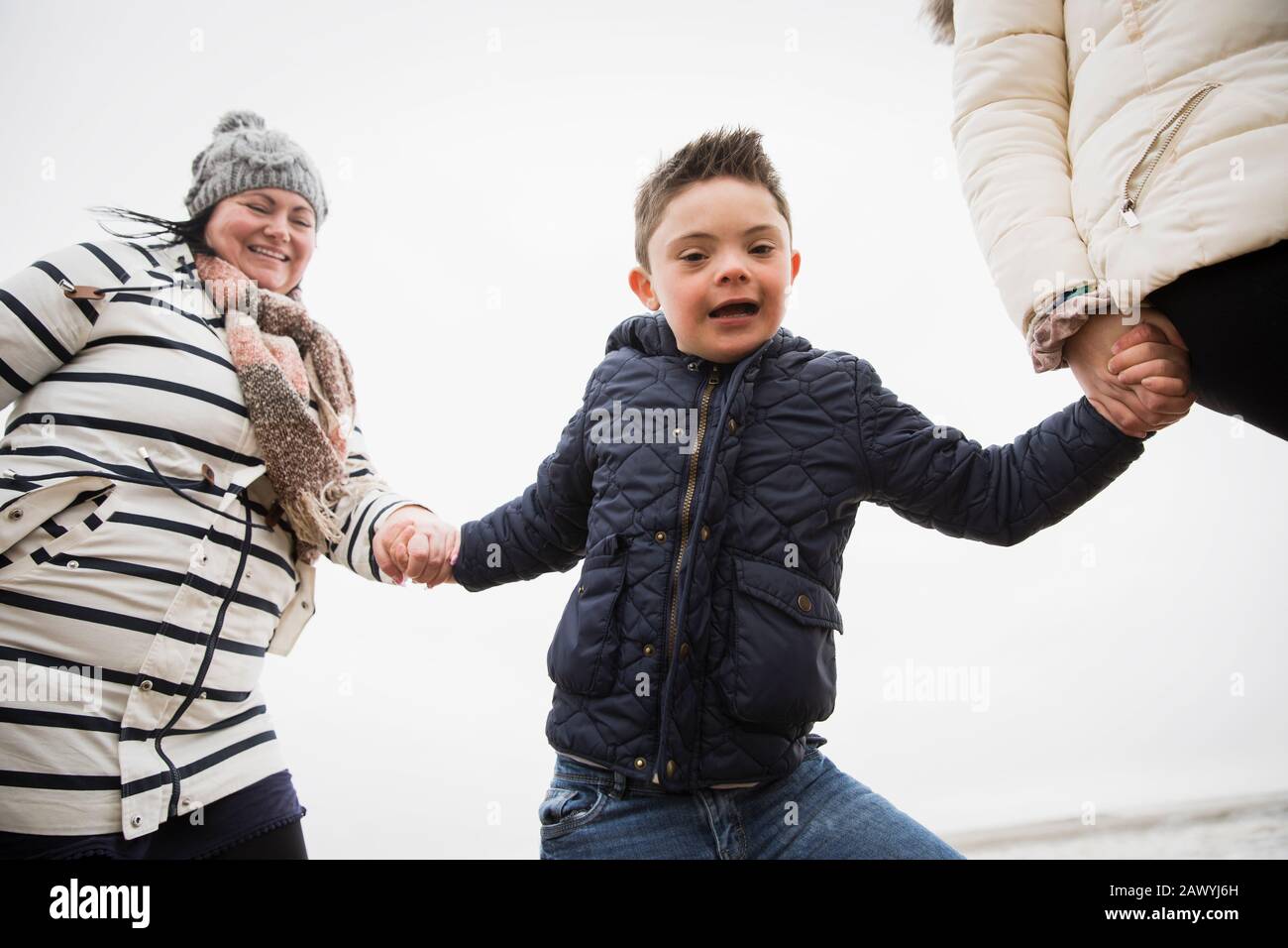 Portrait happy carefree boy with Down Syndrome holding hands with mom Stock Photo