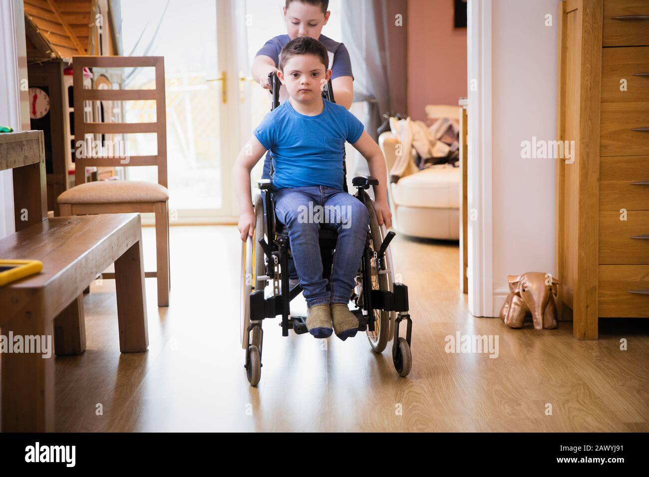 Boy pushing brother with Down Syndrome in wheelchair Stock Photo