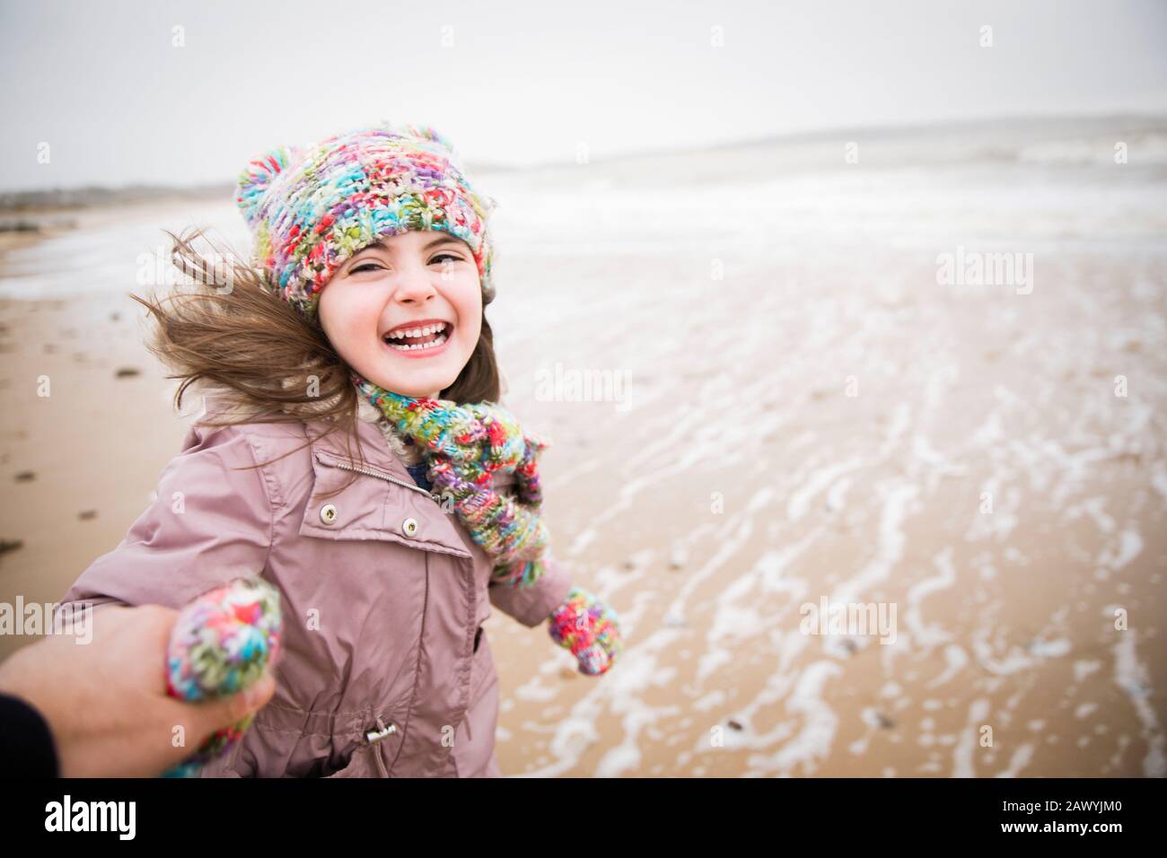 Portrait happy carefree girl running on winter beach Stock Photo
