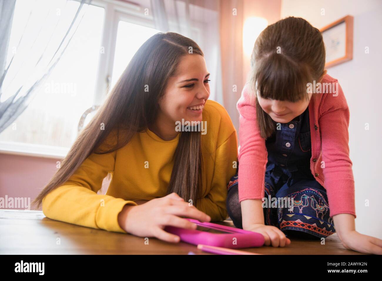 Happy sisters using digital tablet at table Stock Photo