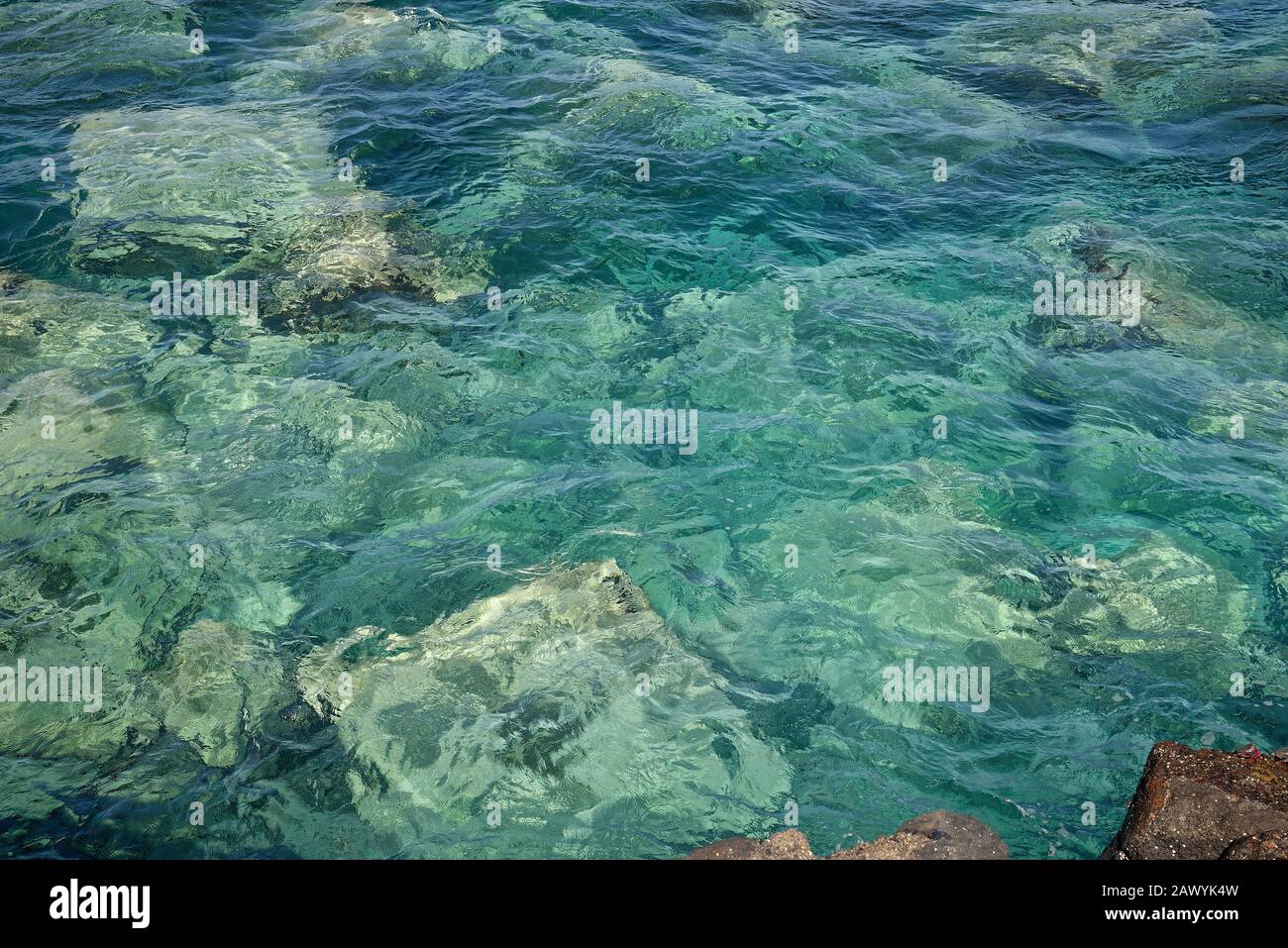 A sea green water scene with rocks below. Suitable as a background image. Stock Photo