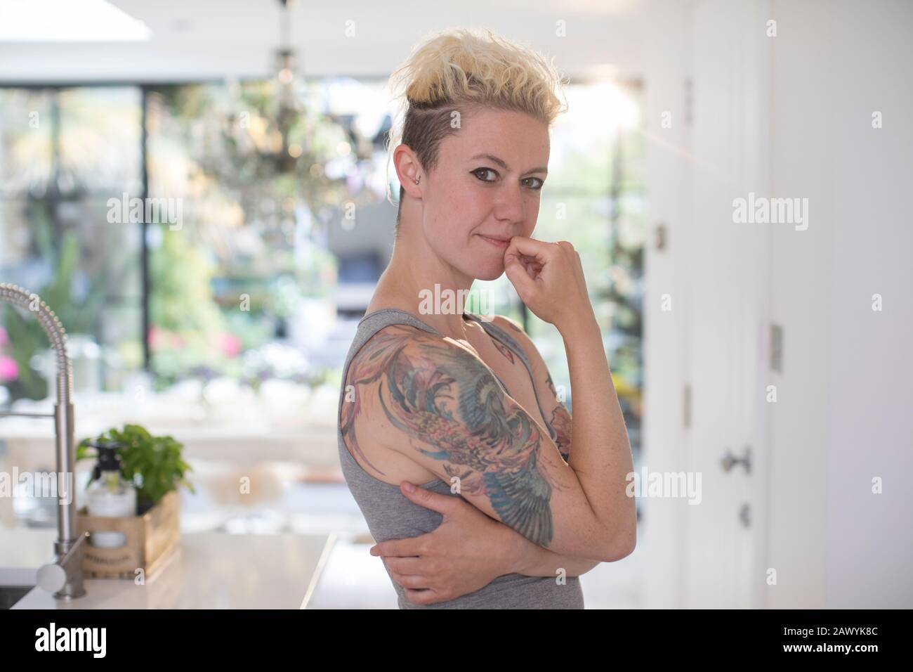 Portrait confident woman with tattoos in kitchen Stock Photo