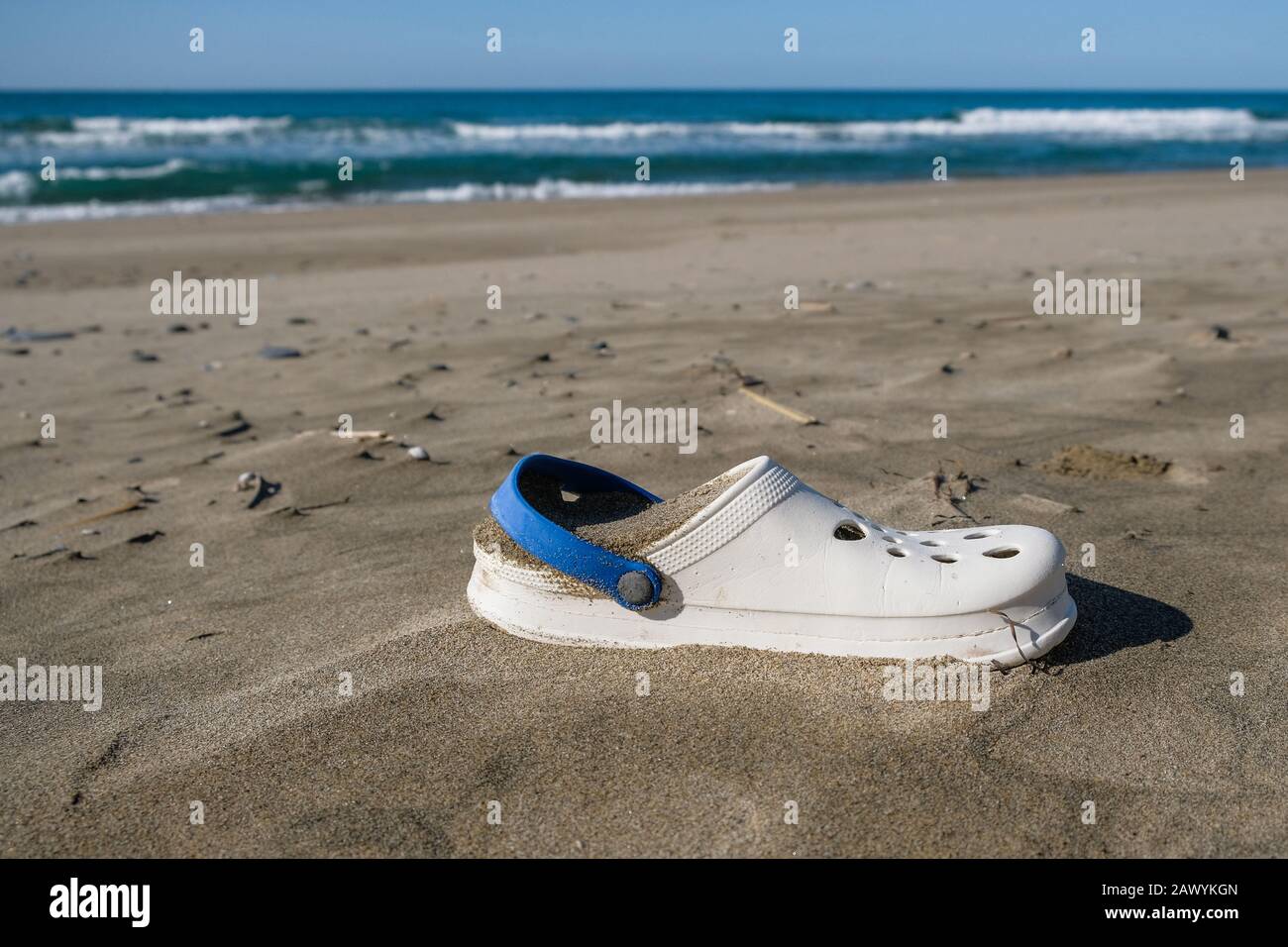 Palinuro,italy - february 10 2020: Summer slippers trash on wild polluted sea coast ecosystem after sea storm,italy Stock Photo