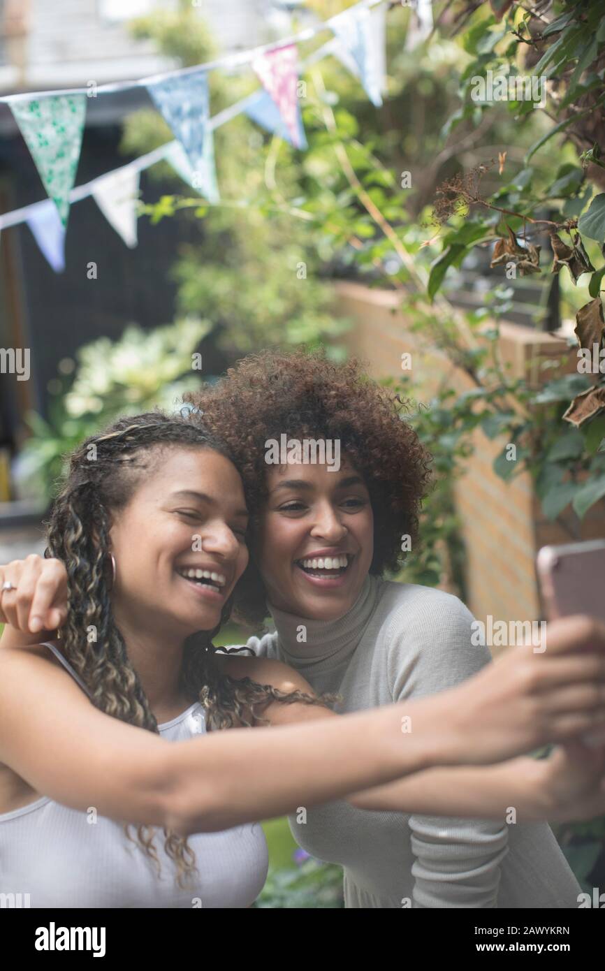 Happy carefree young women friends taking selfie with camera phone Stock Photo