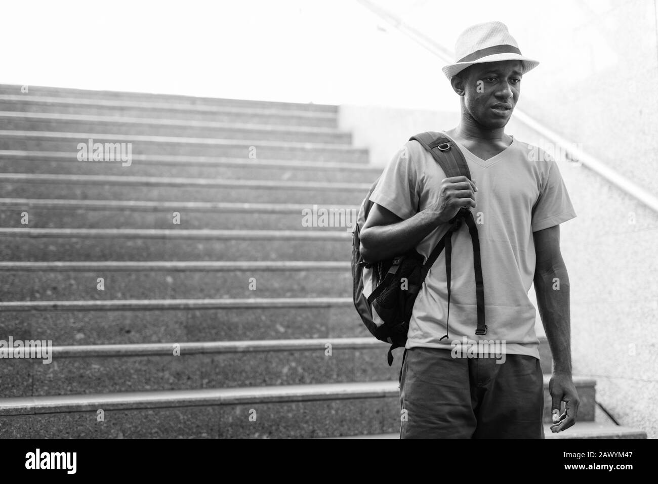 Young African tourist man going down the stairs to subway train station Stock Photo