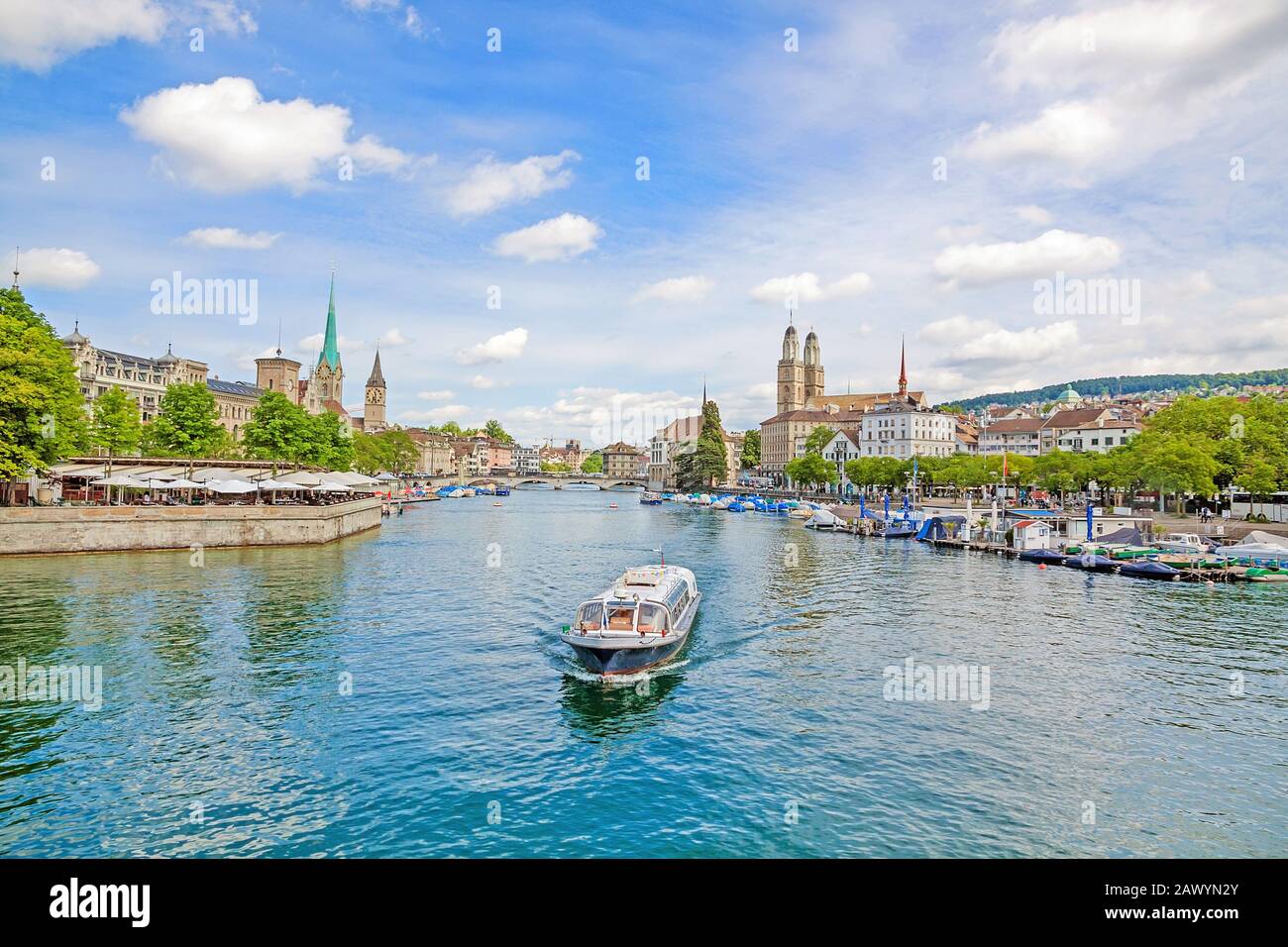 Panoramic view of historic Zurich city center with famous Grossmunster, Fraumunster, St. Peter church. Cruise vessel on river Limmat in front on a sun Stock Photo