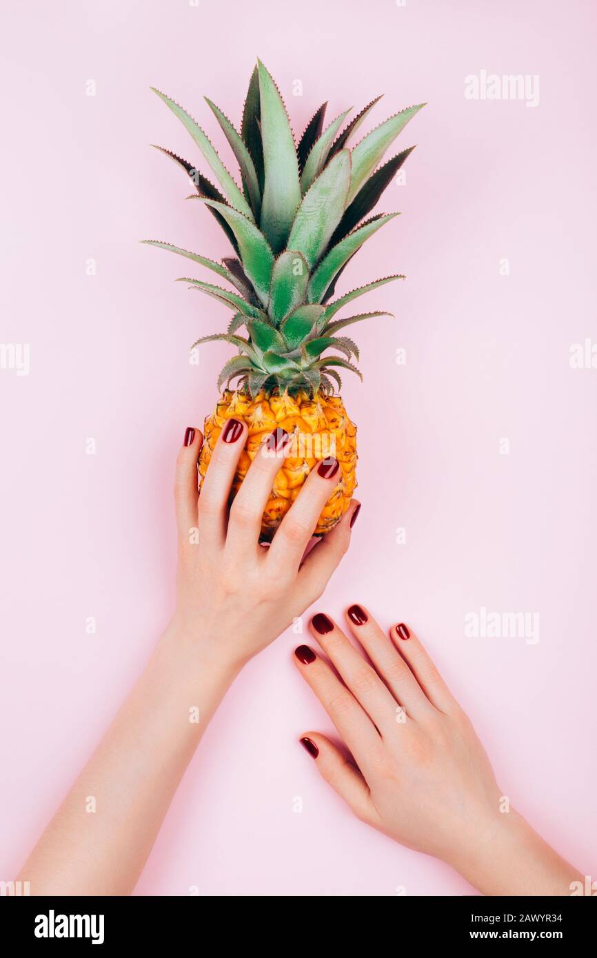 Hands with pineapple on stylish pink background. Stock Photo