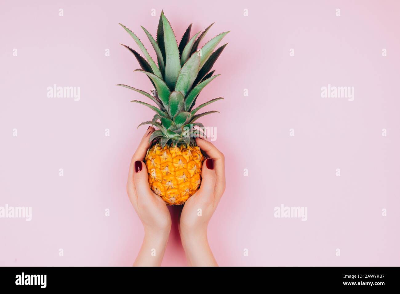 Hands with pineapple on stylish pink background. Stock Photo