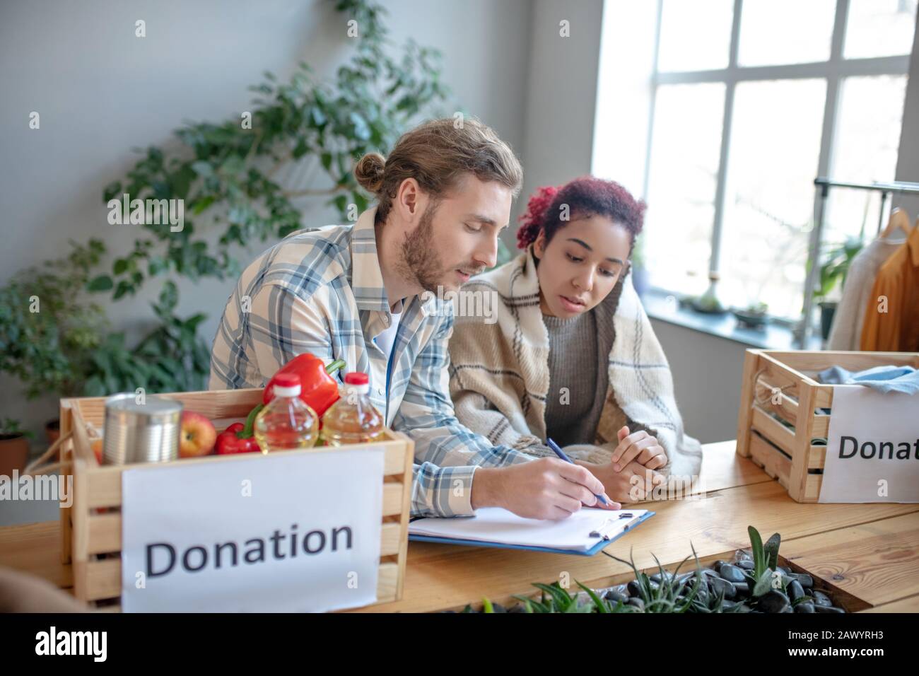 Young man with writing-pad and girl sitting deciding social issues. Stock Photo