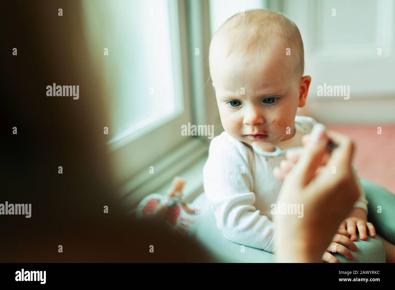 Mother feeding serious baby daughter Stock Photo
