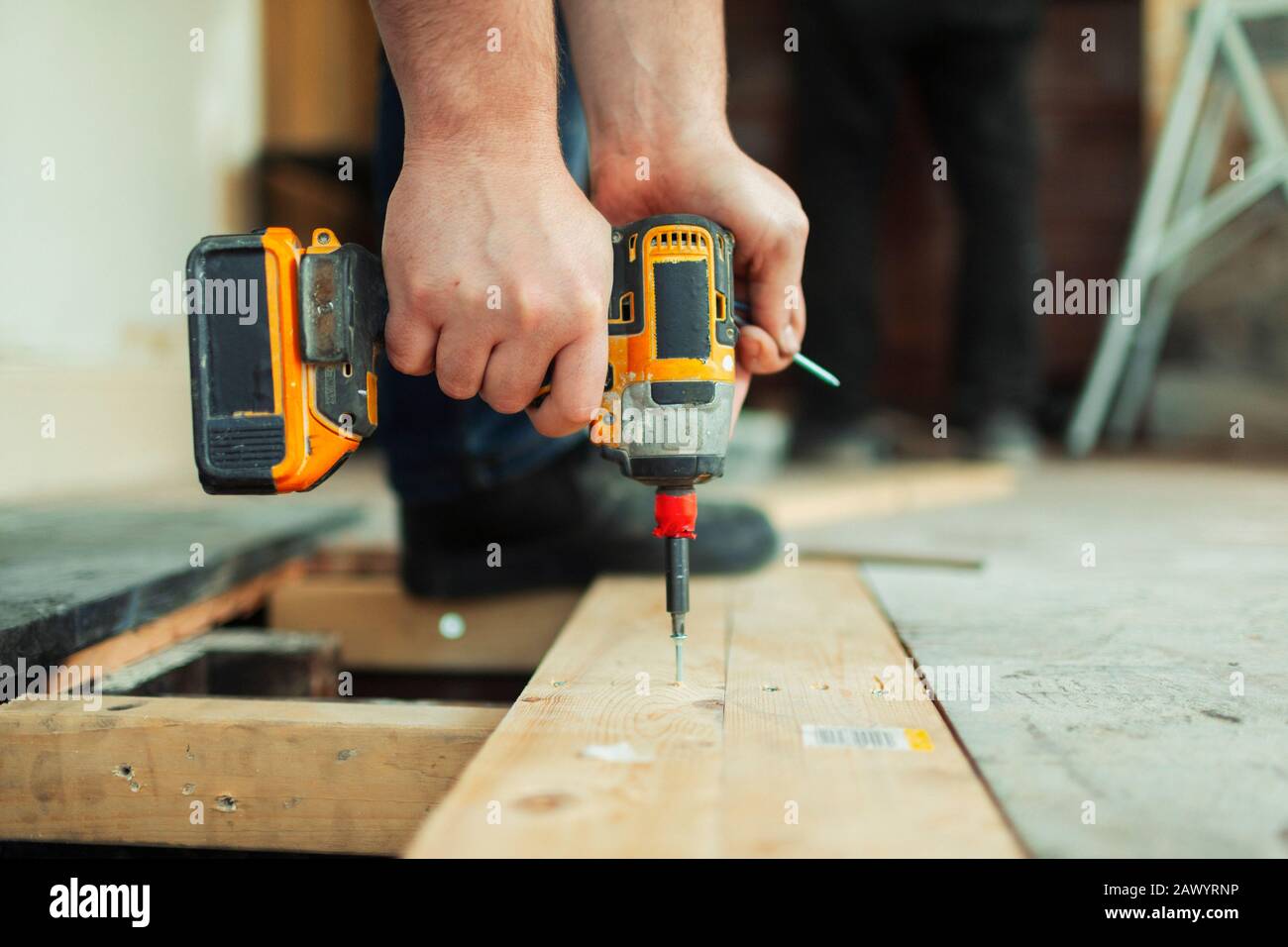 Close up construction worker using power drill installing floorboard Stock Photo