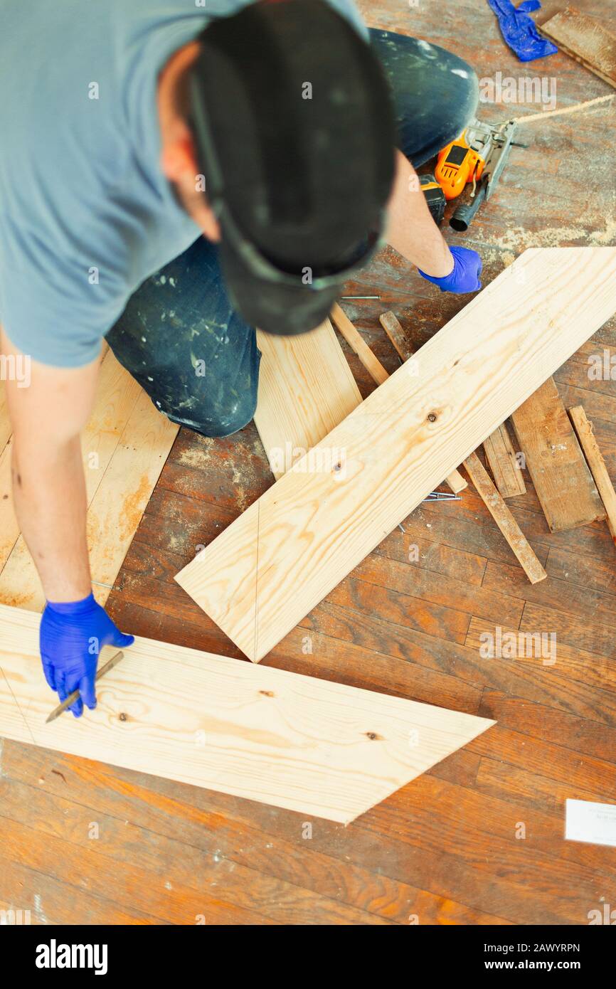 Carpenter marking and cutting floorboards at construction site Stock Photo