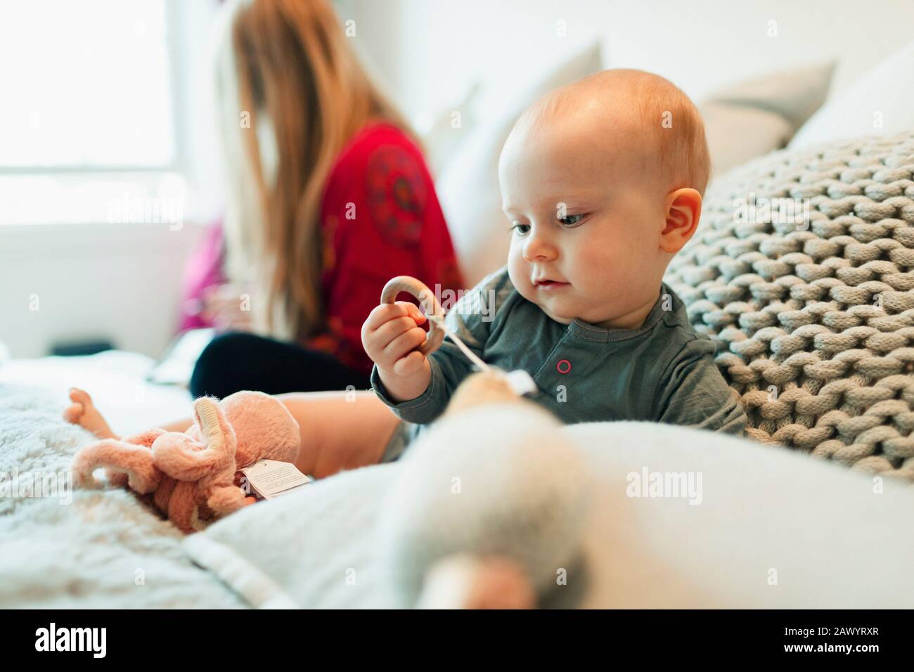 Cute curious baby girl playing with toys on bed Stock Photo