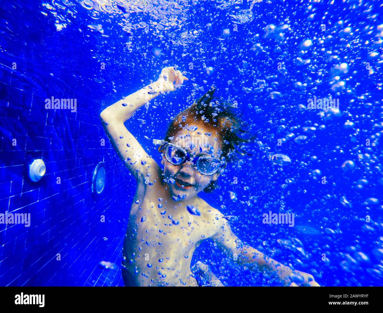 Portrait playful boy swimming underwater in blue swimming pool Stock Photo