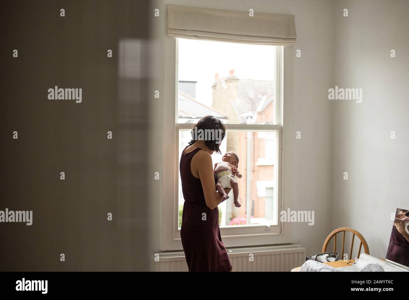Mother holding innocent newborn baby boy at window Stock Photo