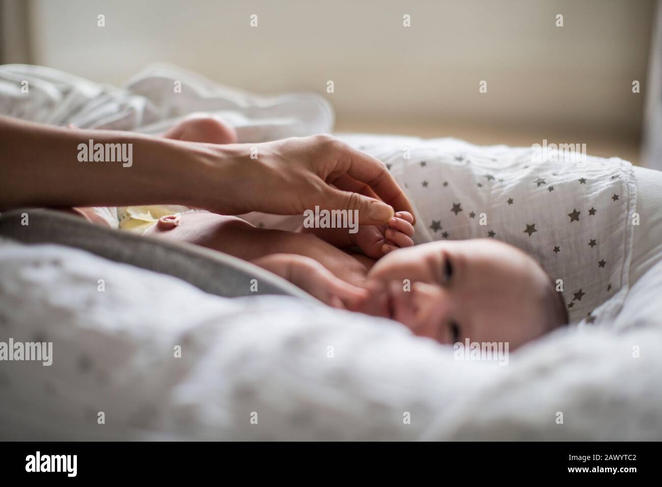 Mother touching innocent newborn baby boy in bassinet Stock Photo