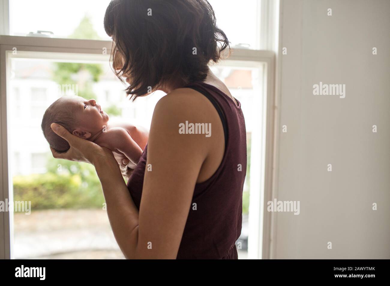Mother cradling newborn baby son at window Stock Photo
