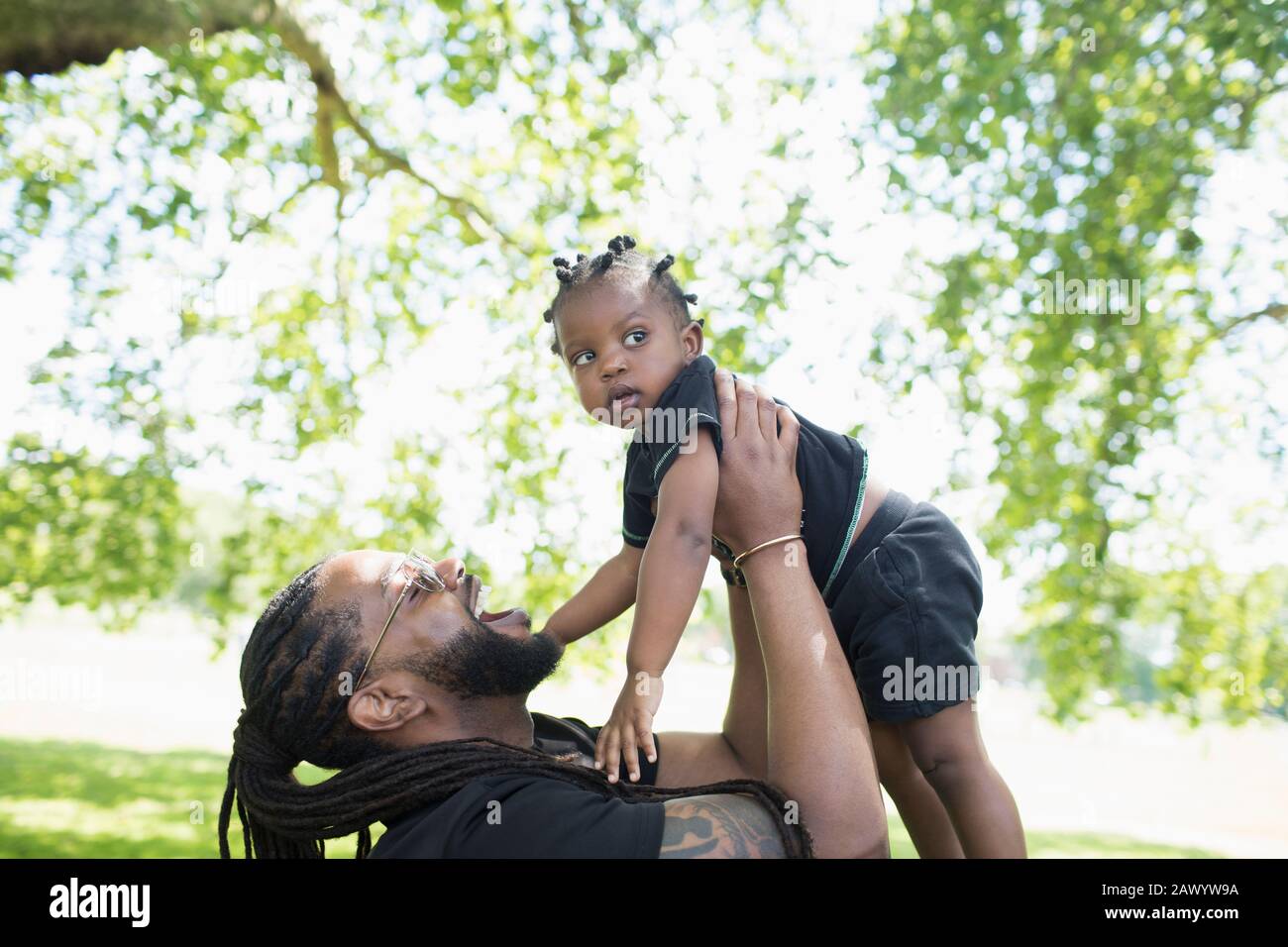 Playful father holding toddler son in park Stock Photo