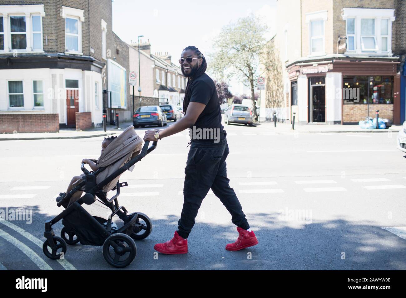 Portrait happy father pushing toddler son in stroller on sunny urban street Stock Photo