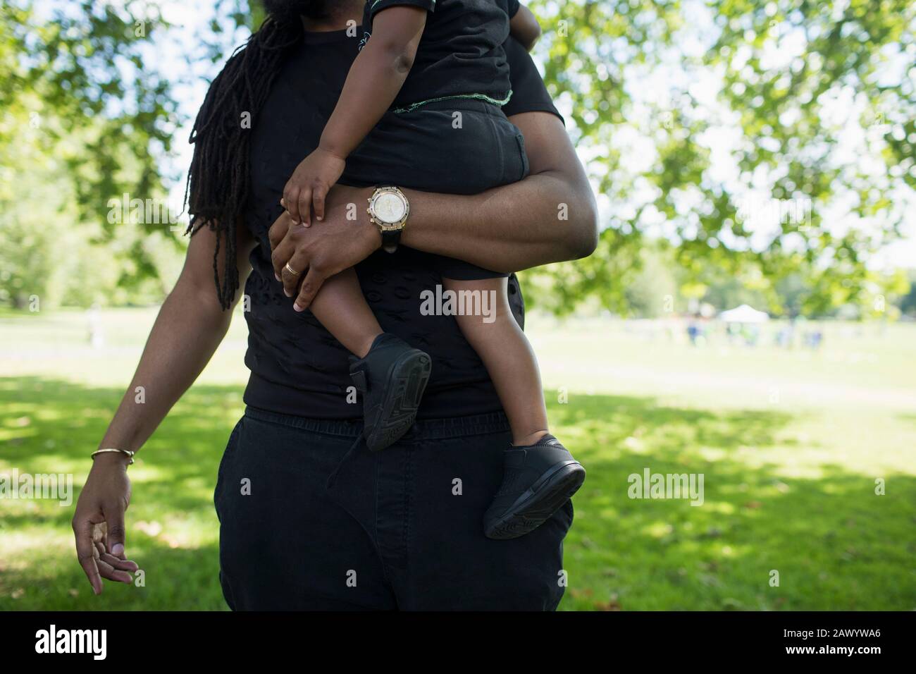 Father carrying toddler son in park Stock Photo
