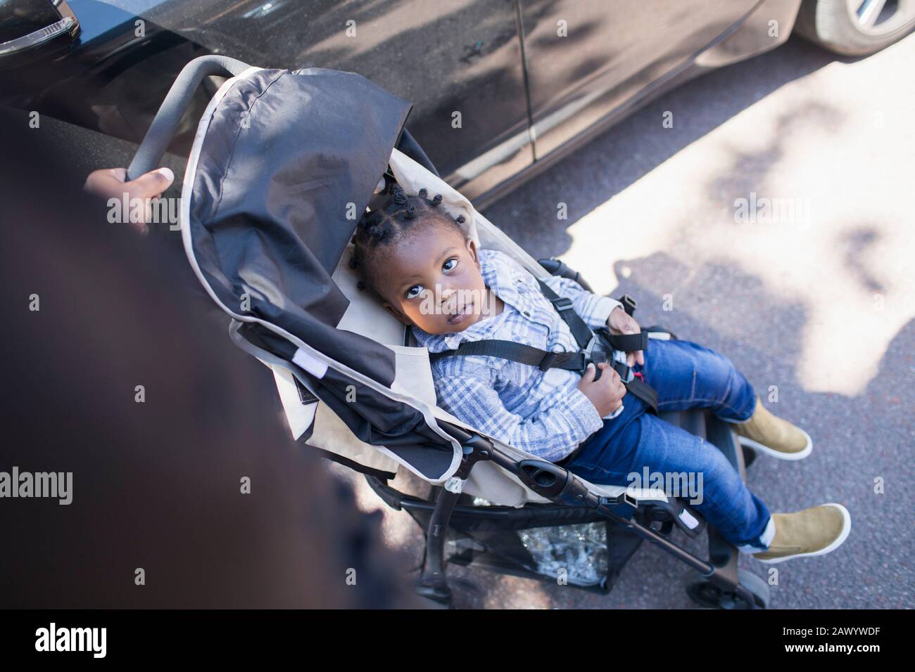 Cute toddler boy in stroller on sidewalk Stock Photo
