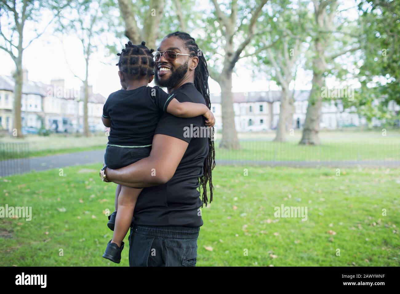 Portrait happy father holding toddler son in park Stock Photo