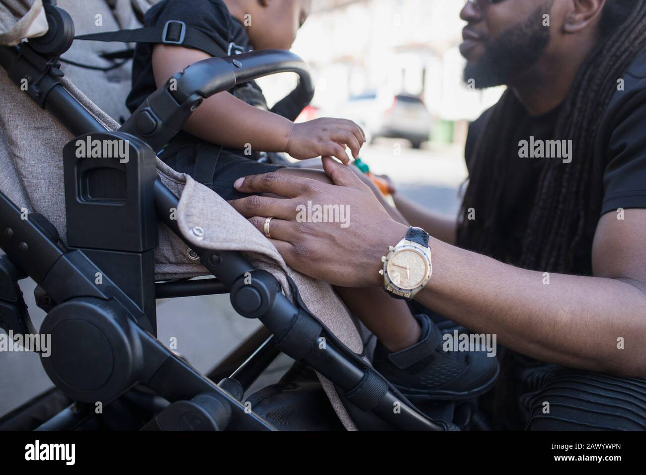 Father talking to toddler son in stroller Stock Photo