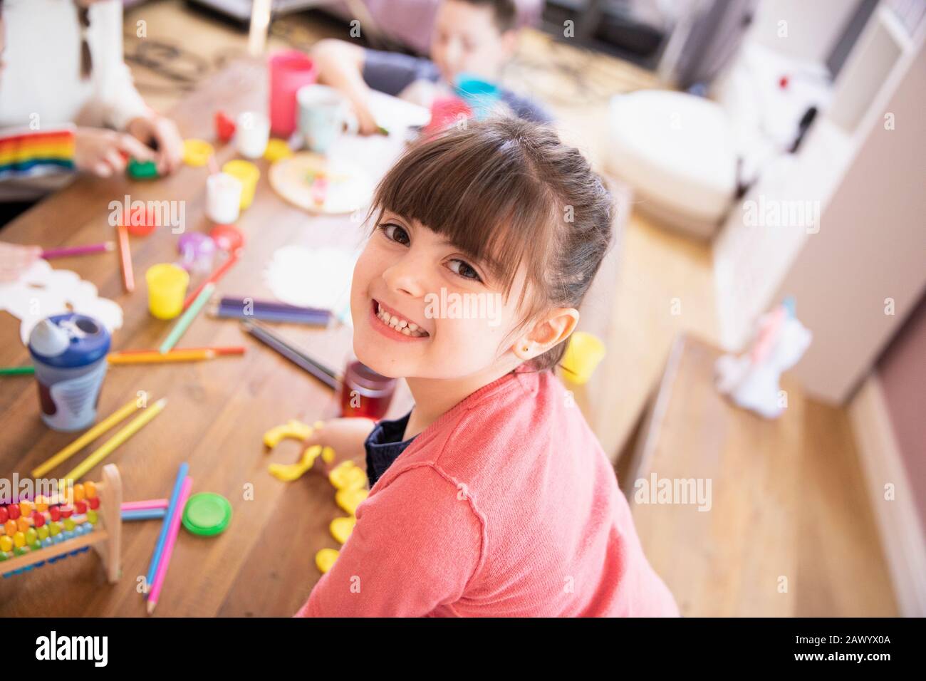 Portrait happy enthusiastic girl playing with toys at table Stock Photo