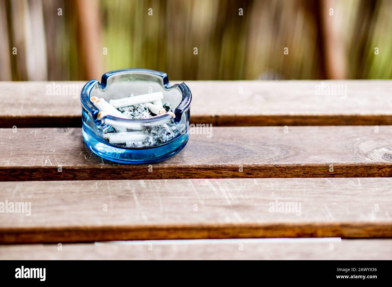 Blue ashtray on a wooden bench in the park Stock Photo